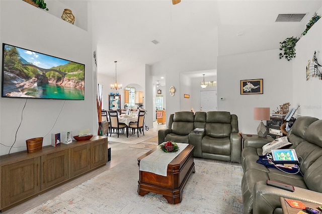 living room with light wood-type flooring, high vaulted ceiling, and an inviting chandelier