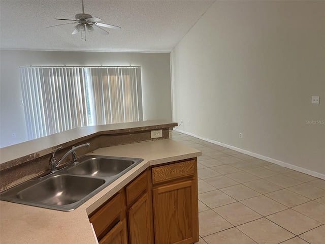 kitchen featuring a textured ceiling, ceiling fan, light tile patterned floors, and sink