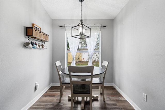 dining room featuring dark hardwood / wood-style flooring, a textured ceiling, and a notable chandelier