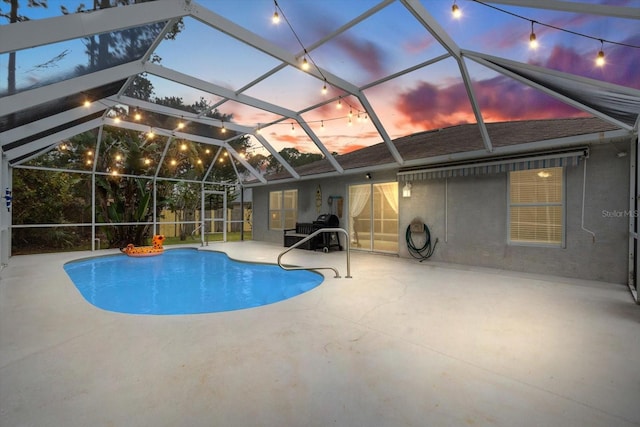 pool at dusk with a lanai and a patio