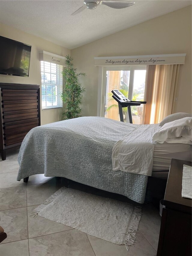 tiled bedroom featuring ceiling fan, vaulted ceiling, a textured ceiling, and access to outside