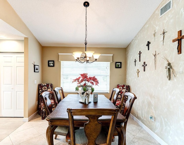 dining space with an inviting chandelier, a textured ceiling, and light tile patterned floors