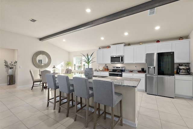 kitchen with light stone countertops, appliances with stainless steel finishes, sink, a center island with sink, and white cabinets