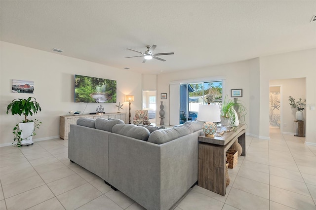 living room with ceiling fan, light tile patterned flooring, and a textured ceiling