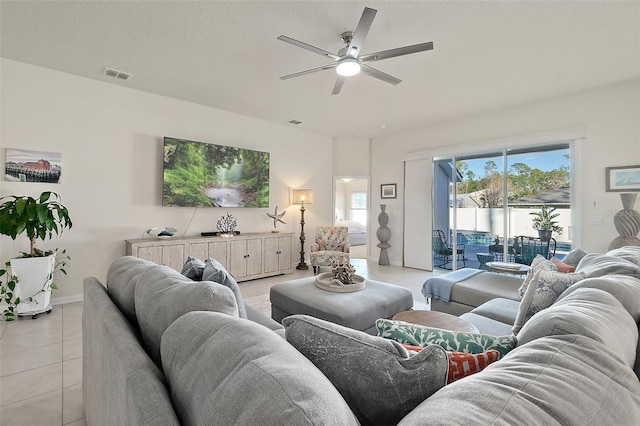 living room with ceiling fan, light tile patterned floors, and a textured ceiling