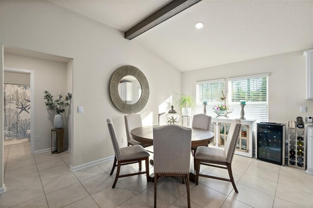 dining space with vaulted ceiling with beams, light tile patterned flooring, and beverage cooler