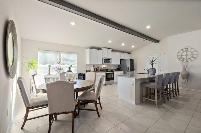 tiled dining space featuring lofted ceiling with beams and sink