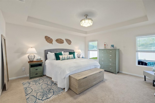 carpeted bedroom with multiple windows and a tray ceiling