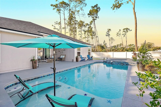 pool at dusk featuring a patio area and an in ground hot tub