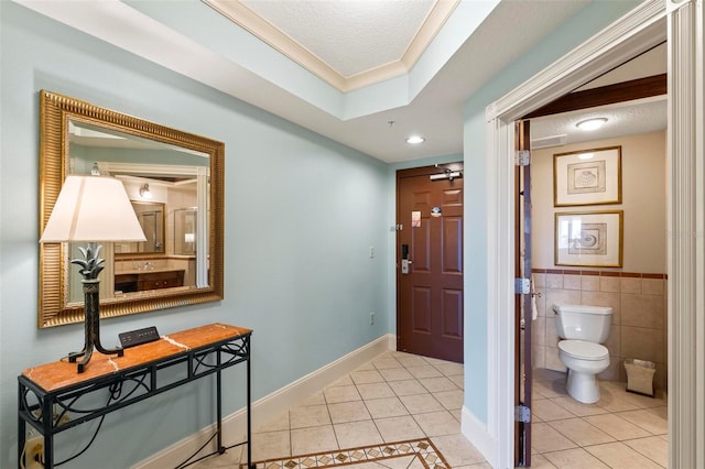 tiled foyer entrance with a textured ceiling, crown molding, and tile walls