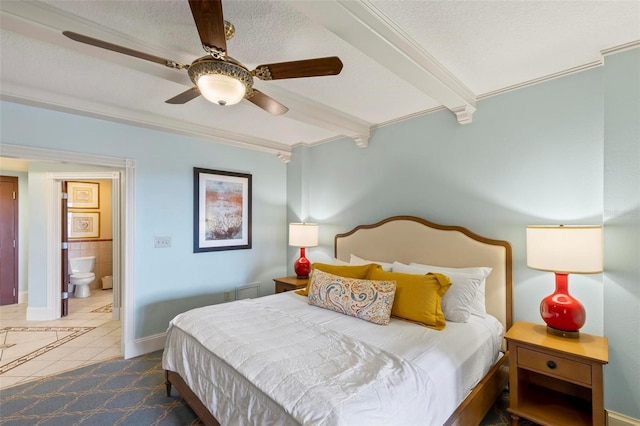 bedroom with ensuite bath, a textured ceiling, ceiling fan, dark tile patterned flooring, and beamed ceiling