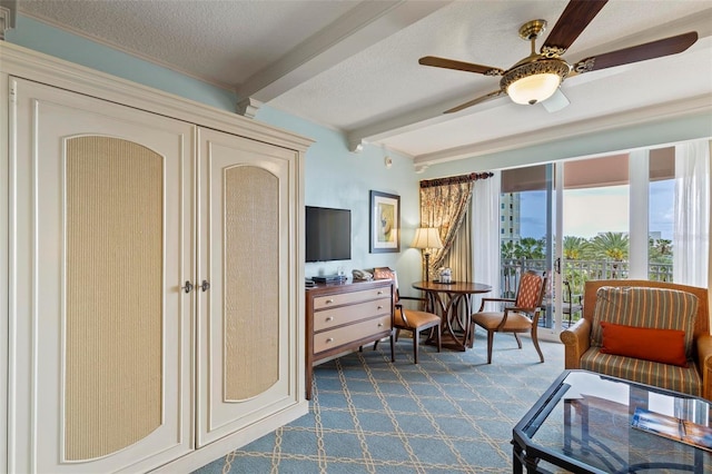 sitting room with beam ceiling, ceiling fan, dark carpet, and a textured ceiling
