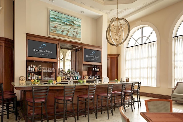 bar featuring light stone countertops, light tile patterned floors, and a tray ceiling
