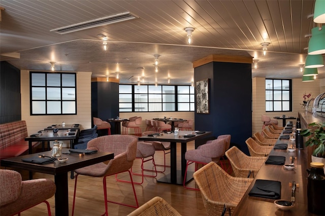 dining room featuring hardwood / wood-style floors, wood walls, and wood ceiling