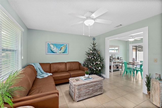 living room featuring light tile patterned floors, a textured ceiling, and ceiling fan