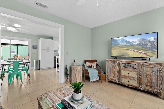 living room with a textured ceiling, ceiling fan, and light tile patterned flooring