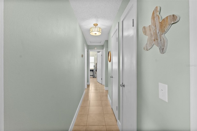 hallway featuring light tile patterned floors and a textured ceiling