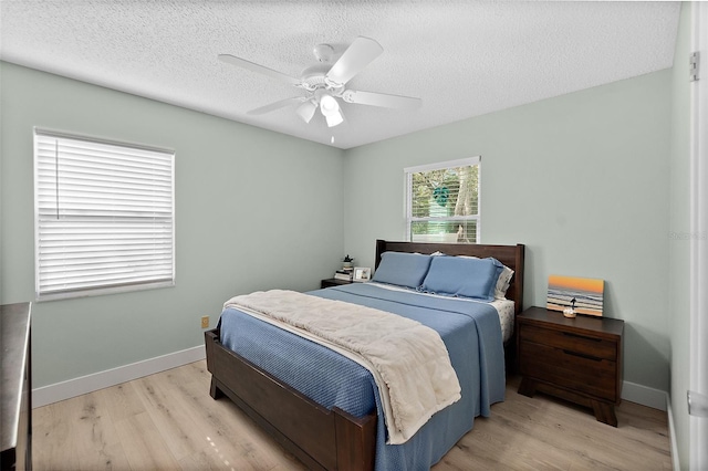 bedroom featuring ceiling fan, light hardwood / wood-style floors, and a textured ceiling