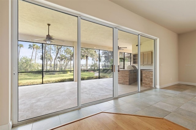 doorway to outside with plenty of natural light, ceiling fan, and light tile patterned flooring