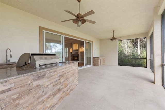 view of patio featuring grilling area, ceiling fan, and exterior kitchen