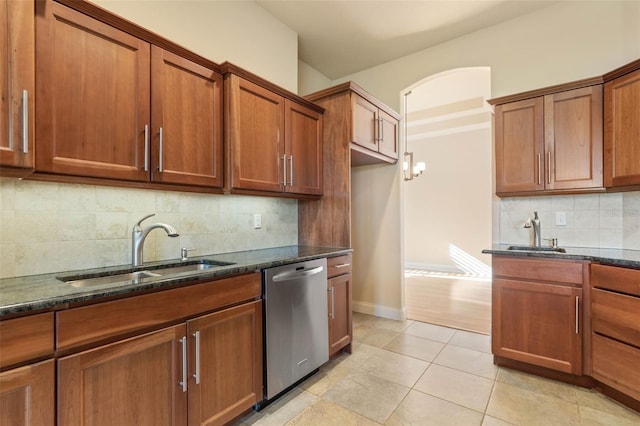 kitchen with dishwasher, dark stone countertops, light tile patterned floors, and sink