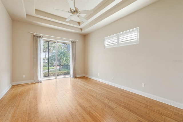 spare room featuring ceiling fan, a raised ceiling, and light wood-type flooring