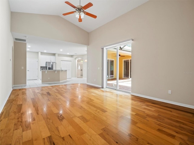 unfurnished living room with ceiling fan, light hardwood / wood-style floors, and high vaulted ceiling