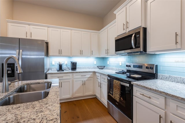 kitchen featuring white cabinets, sink, tasteful backsplash, light stone counters, and stainless steel appliances