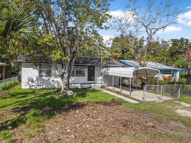 back of house featuring a carport and a lawn