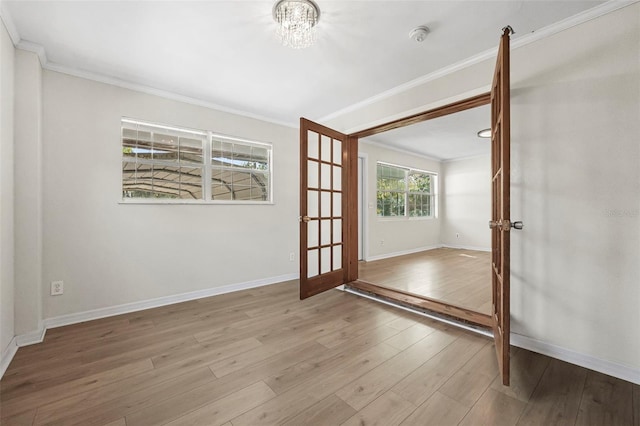 unfurnished room with an inviting chandelier, ornamental molding, and light hardwood / wood-style flooring