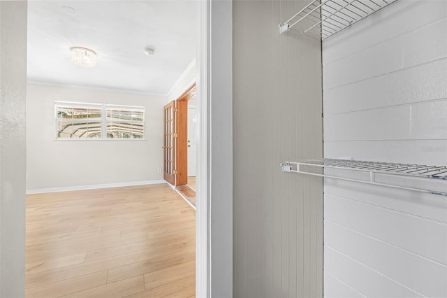 hall with light hardwood / wood-style floors and crown molding