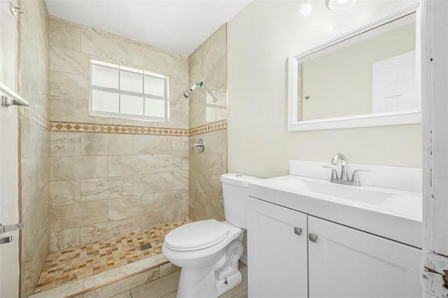 bathroom featuring tiled shower, tile patterned flooring, vanity, and toilet