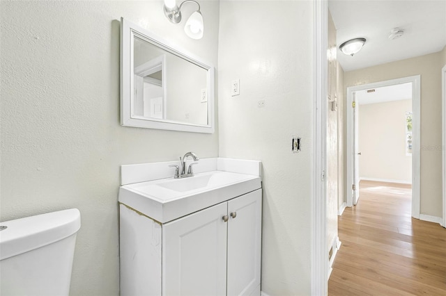 bathroom with toilet, vanity, and hardwood / wood-style flooring