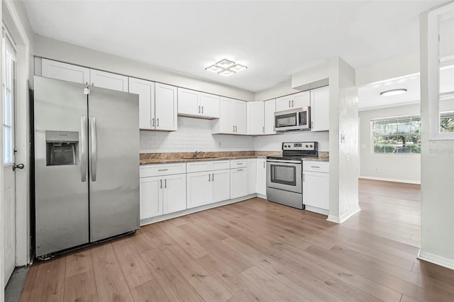 kitchen with white cabinets, appliances with stainless steel finishes, light hardwood / wood-style flooring, and sink