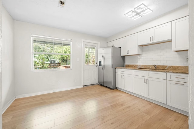 kitchen with backsplash, white cabinets, sink, stainless steel refrigerator with ice dispenser, and light hardwood / wood-style flooring