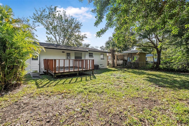 rear view of property with a wooden deck, a yard, and central AC