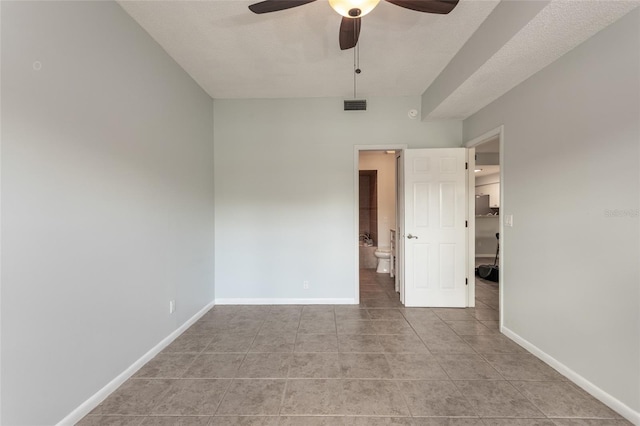 empty room with ceiling fan, a textured ceiling, and light tile patterned floors