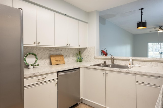 kitchen with sink, pendant lighting, stainless steel appliances, decorative backsplash, and white cabinets