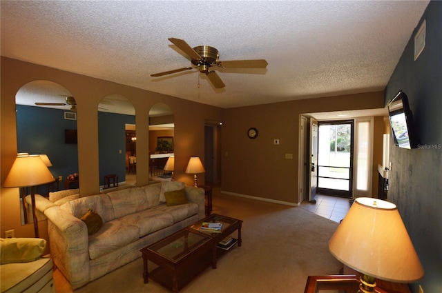 living room with ceiling fan, light carpet, and a textured ceiling