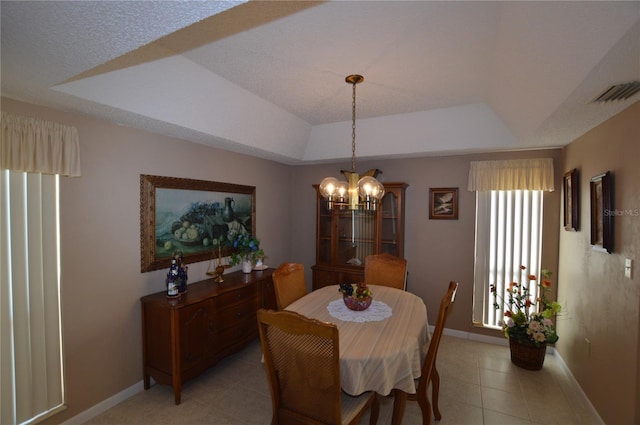 tiled dining room featuring a raised ceiling and a notable chandelier