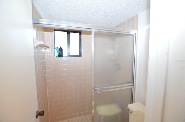 bathroom with a textured ceiling, toilet, and walk in shower