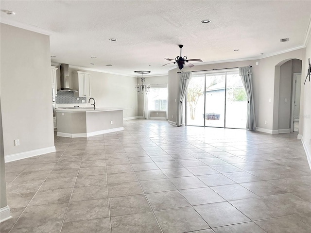 unfurnished living room featuring ornamental molding, a textured ceiling, ceiling fan, sink, and light tile patterned floors