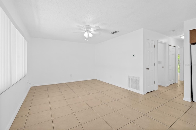 tiled empty room featuring ceiling fan and a textured ceiling