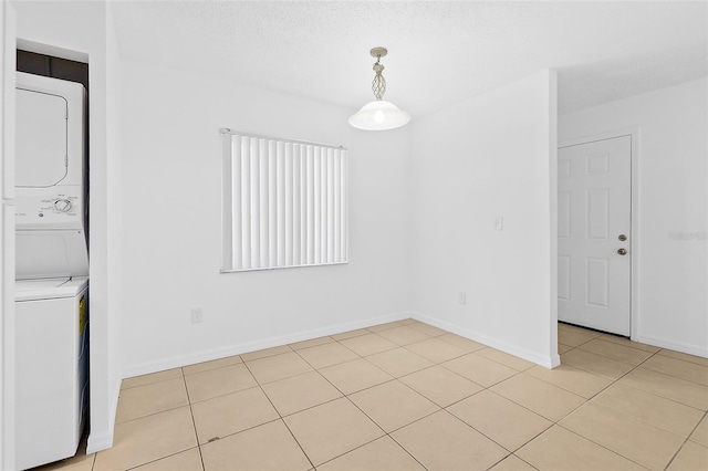 interior space featuring stacked washer and dryer and light tile patterned flooring