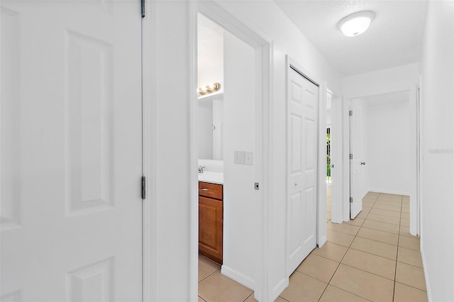 corridor with light tile patterned flooring and a textured ceiling