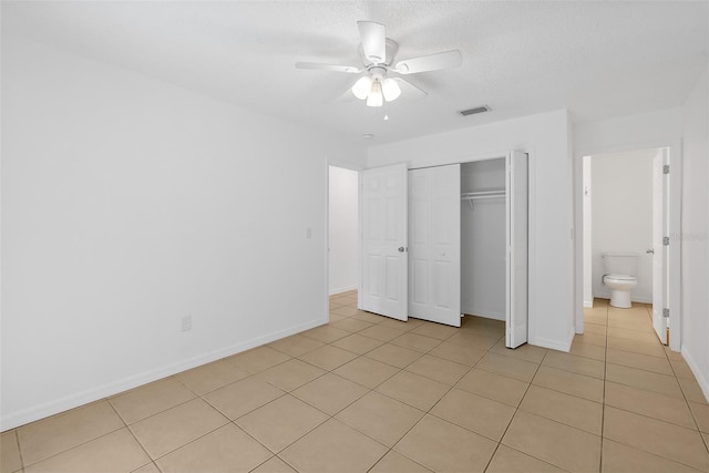 unfurnished bedroom with ensuite bath, ceiling fan, a closet, and light tile patterned floors