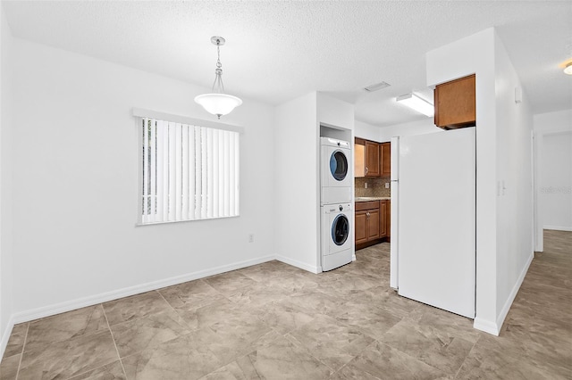 laundry room featuring a textured ceiling and stacked washer / drying machine