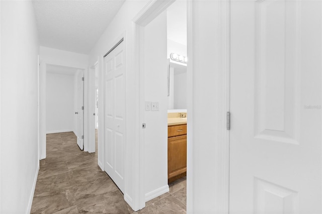 hallway with a textured ceiling and sink