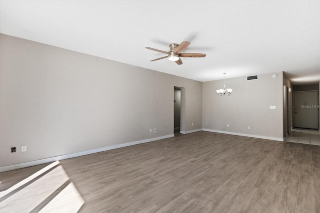 spare room with hardwood / wood-style floors and ceiling fan with notable chandelier