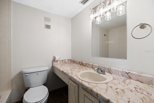 full bathroom with vanity, toilet, a textured ceiling, and tiled shower / bath combo